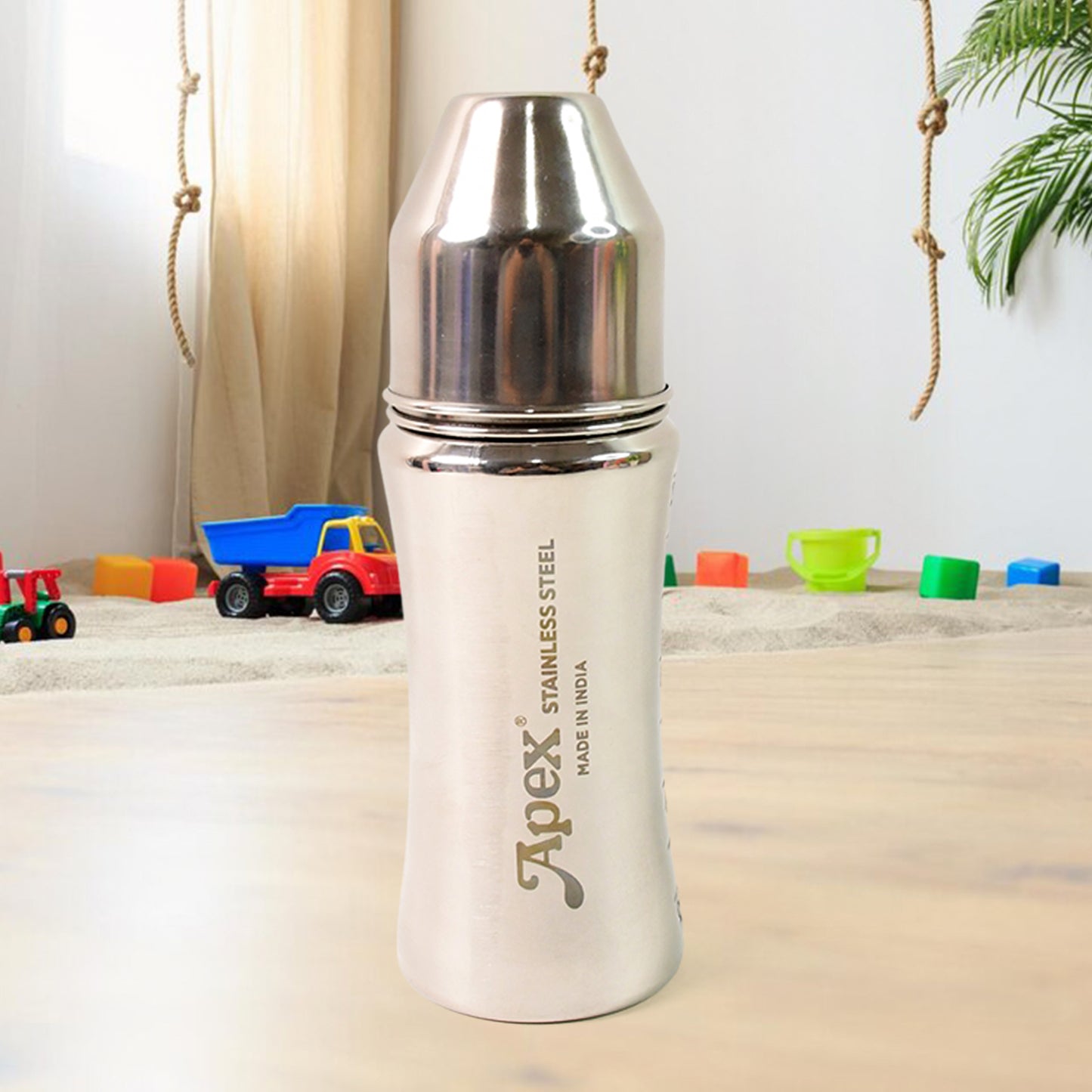 stainless steel baby feeding bottle insulated with ergonomic grip shown on nursery table with toys
