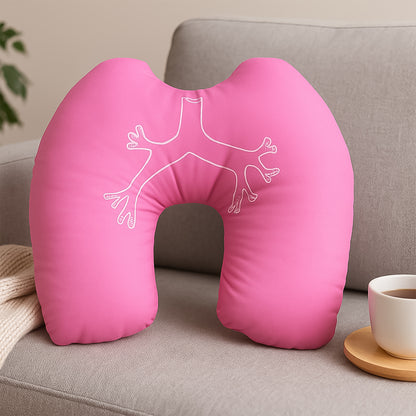 pink travel neck pillow for airplanes with white bronchial design on gray sofa