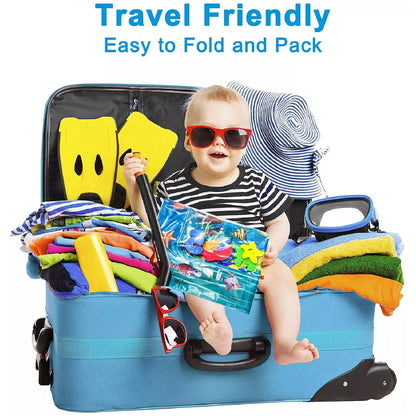 baby water play mat with toddler in sunglasses sitting inside a packed travel suitcase