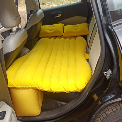 yellow inflatable bed with two pillows installed in compact car using portable car air mattress for back seat
