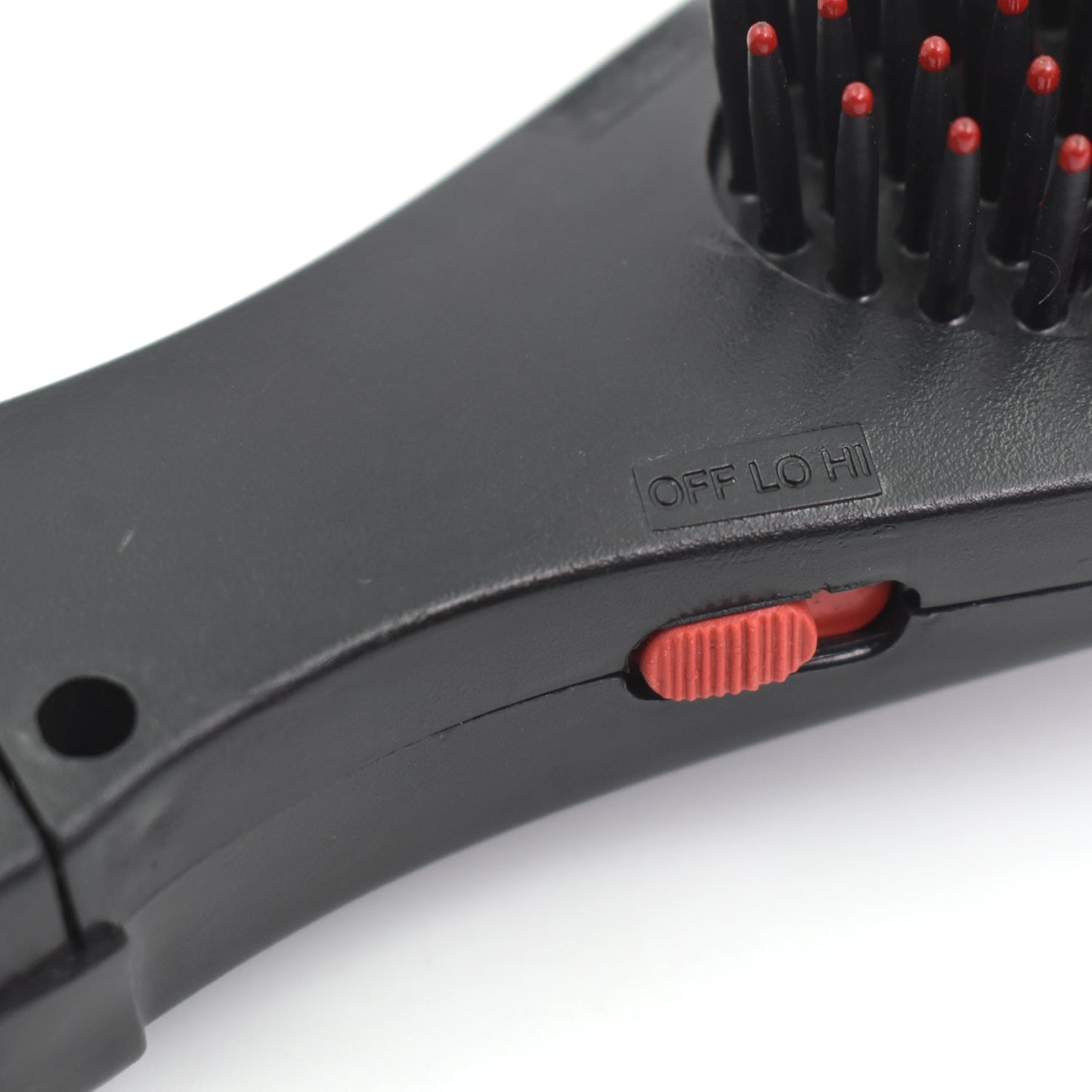 black hair brush with massage function close up showing red bristle tips and red speed switch