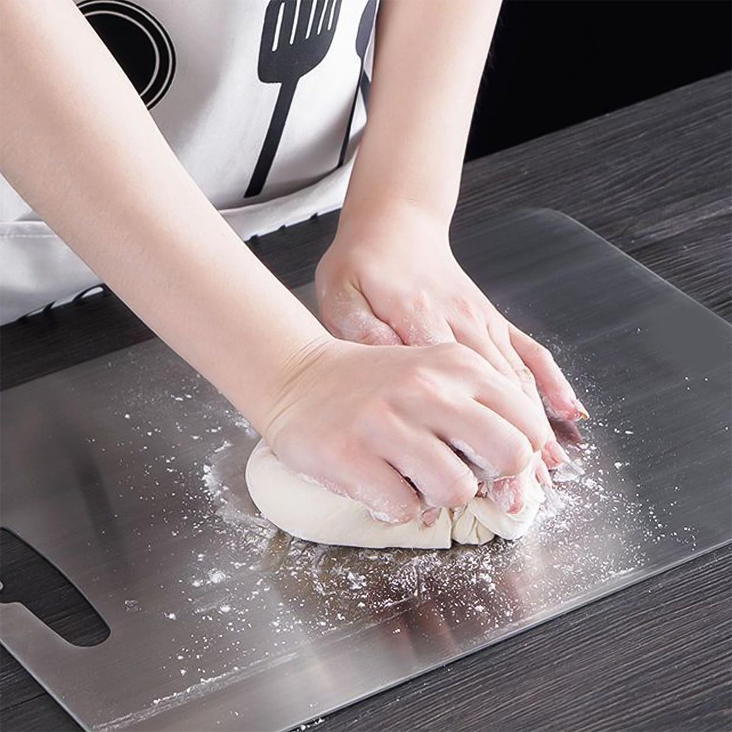 stainless steel chopping board with hands kneading dough on flat hygienic surface for baking