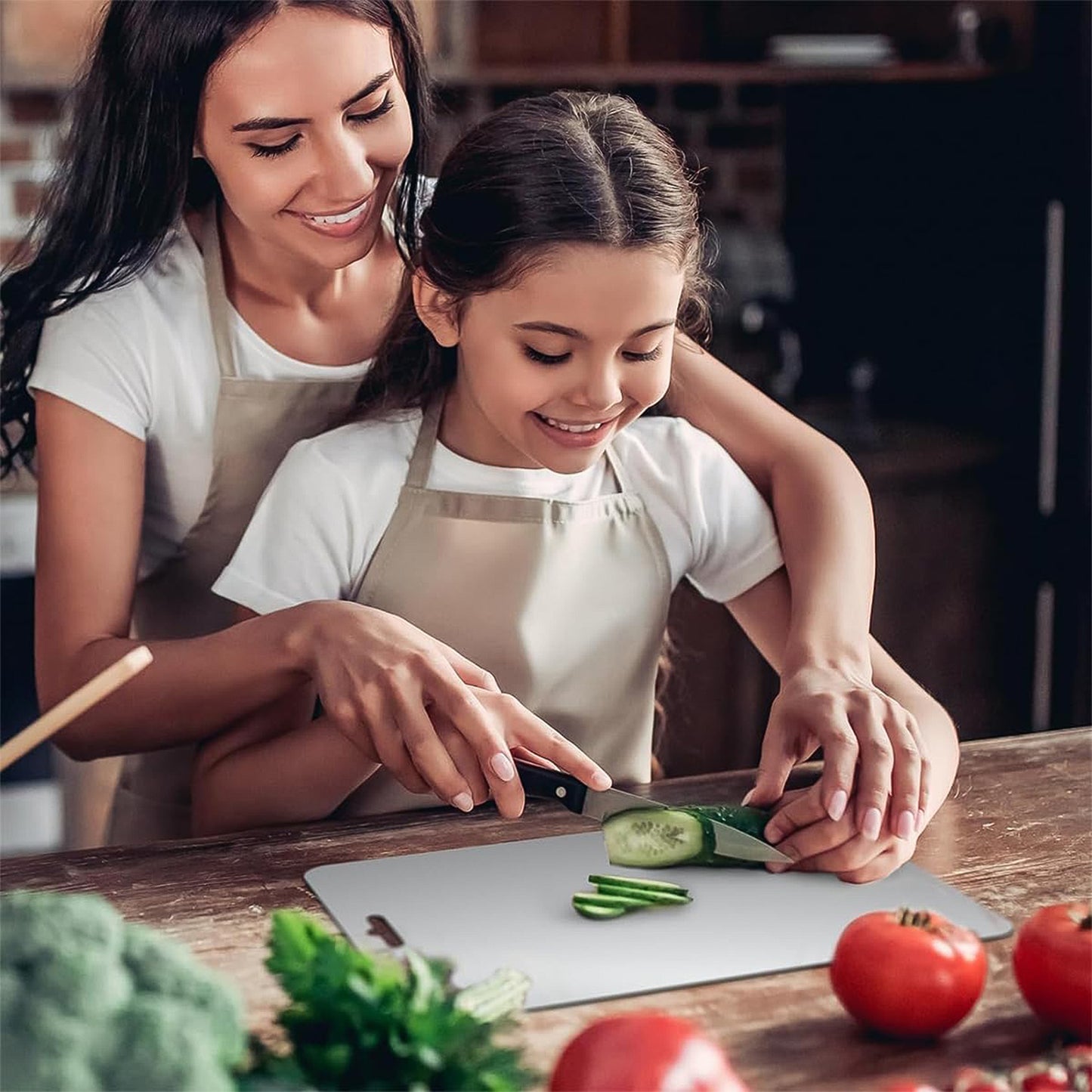 stainless steel chopping board with mother teaching child to slice cucumber on countertop