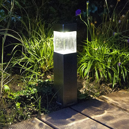 stainless steel garden bollard illuminated on wooden path at night weatherproof solar park lighting