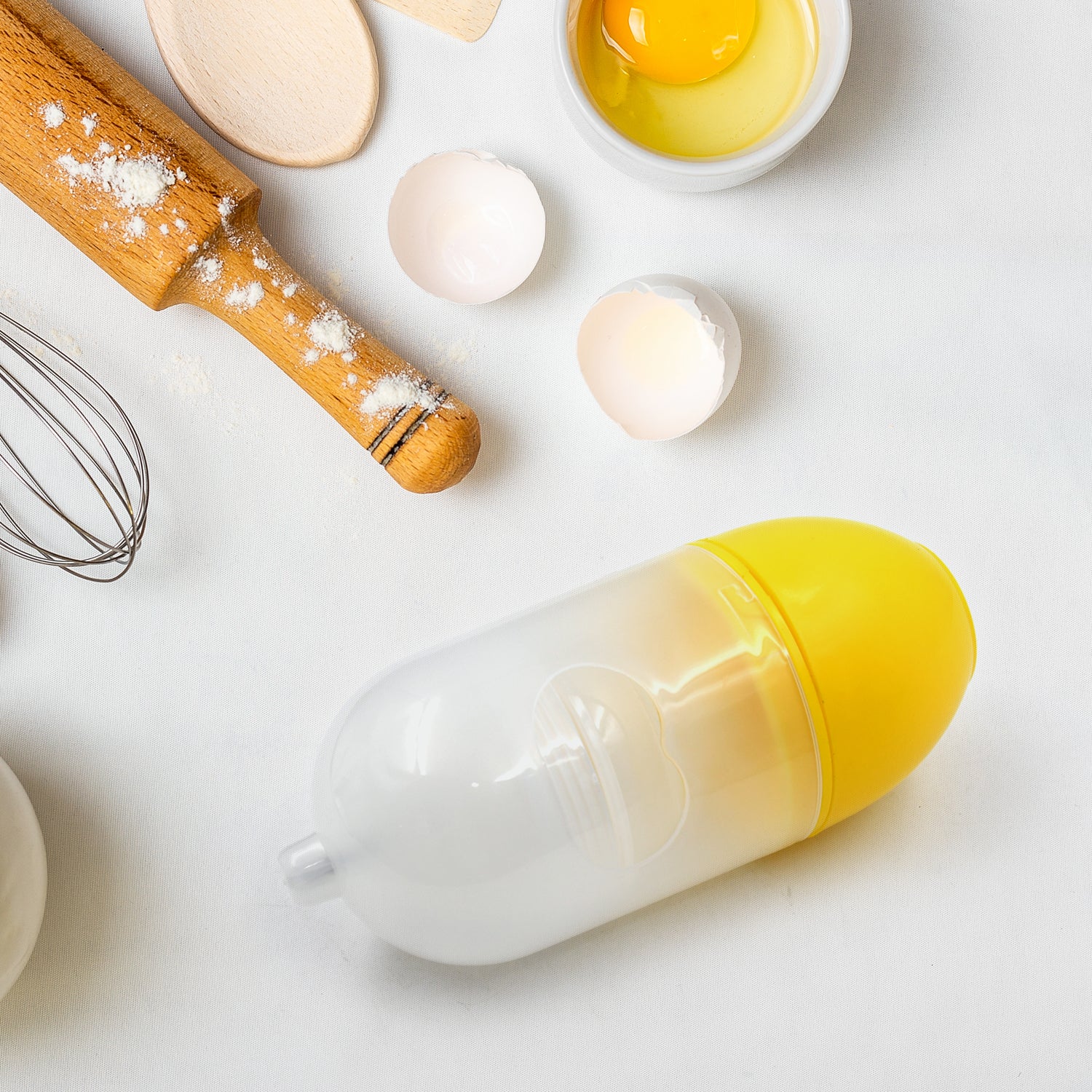 household egg puller gadget clear yellow egg shaped tool on kitchen counter with cracked eggs and rolling pin
