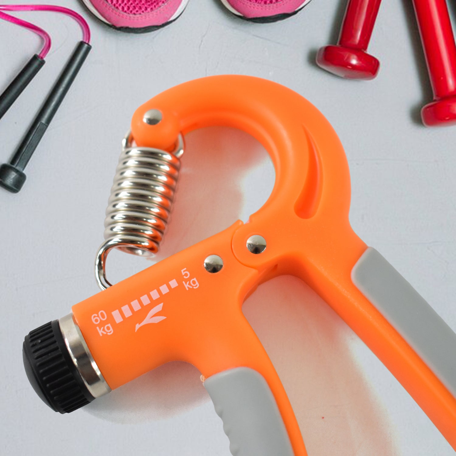 Orange adjustable hand grip with spring and dial near jump rope and weights best grip strengthener for gym