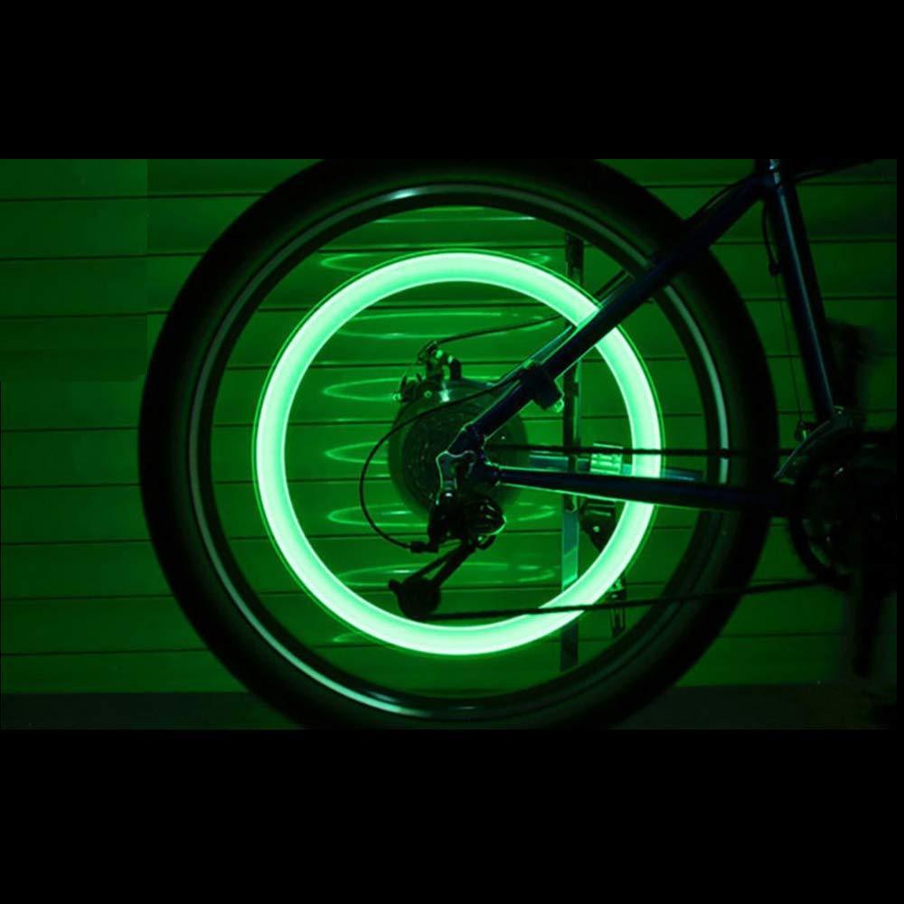 automotive LED bike wheel safety light glowing green mounted on bicycle rear wheel at night