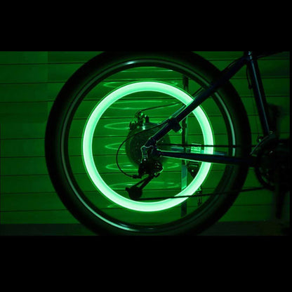 automotive LED bike wheel safety light glowing green mounted on bicycle rear wheel at night