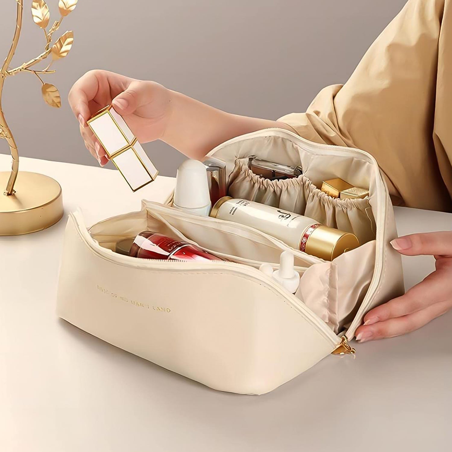 premium cream makeup bag open with organized compartments holding skincare and lipstick