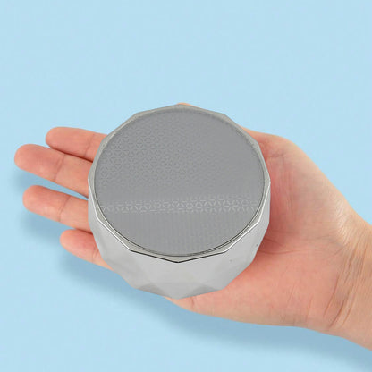 portable skin hair remover device handheld silver round compact with textured top shown in palm