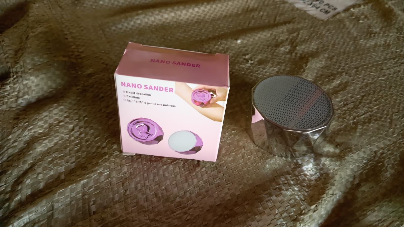portable skin hair remover device Nano Sander with pink retail box and silver round shaver on fabric