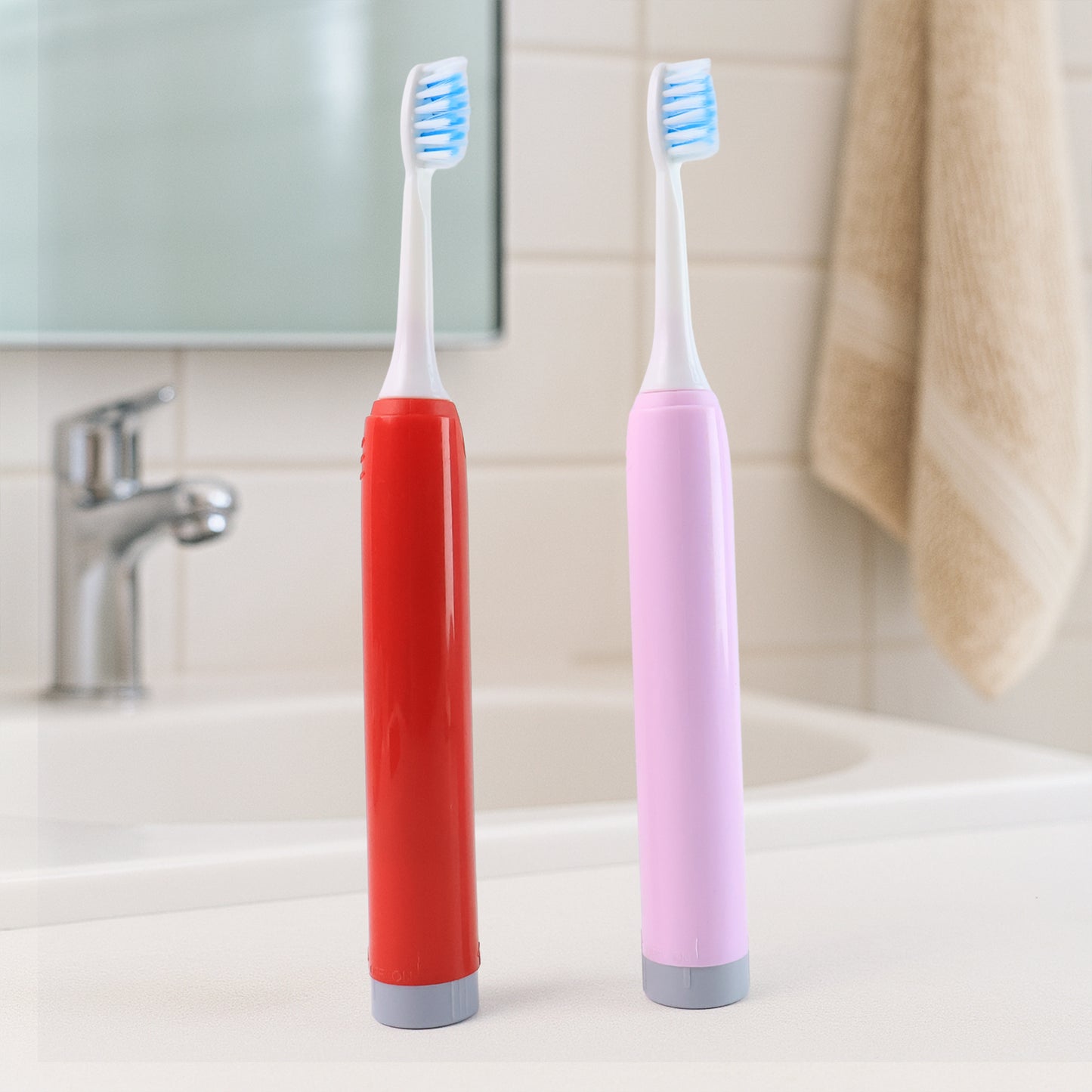 red and pink battery toothbrushes standing on bathroom sink counter with blue bristles best battery toothbrush for adults