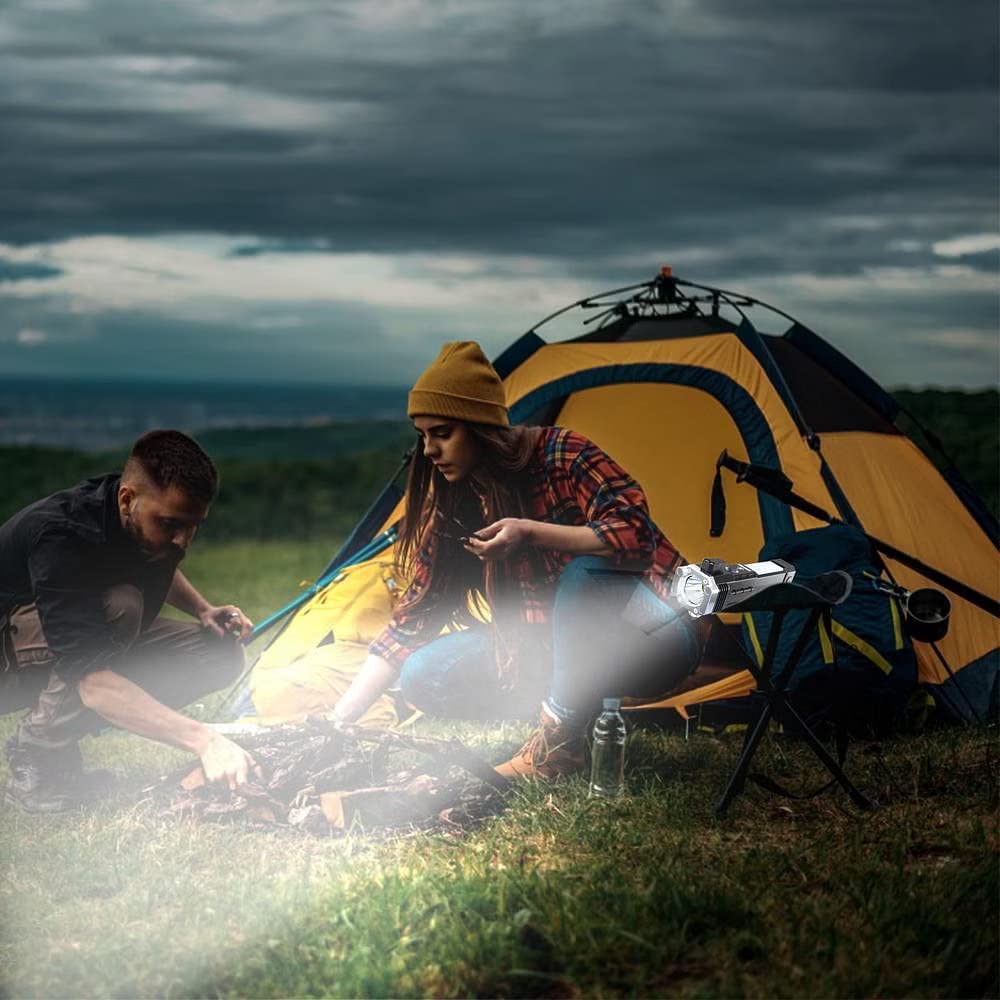 portable rechargeable LED flashlight illuminating campsite near tent while campers prepare fire