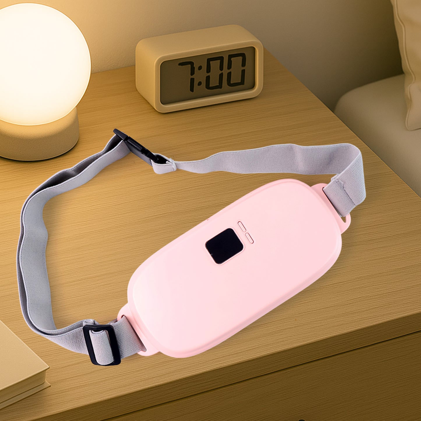 pink pain relief heating belt for women with adjustable gray strap on bedside table