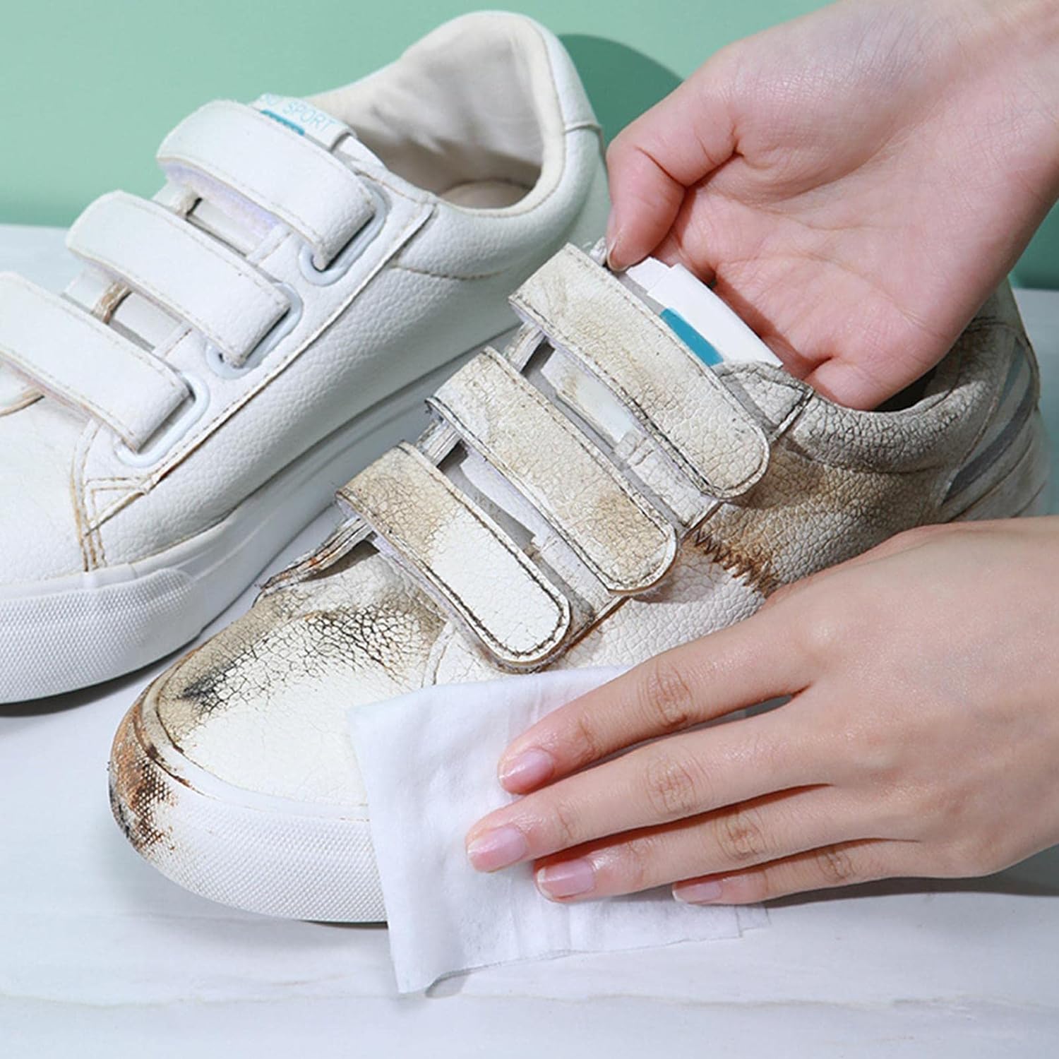 shoe cleaning wipes removing heavy dirt from white velcro sneakers being wiped by hands
