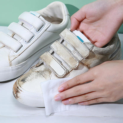 shoe cleaning wipes removing heavy dirt from white velcro sneakers being wiped by hands