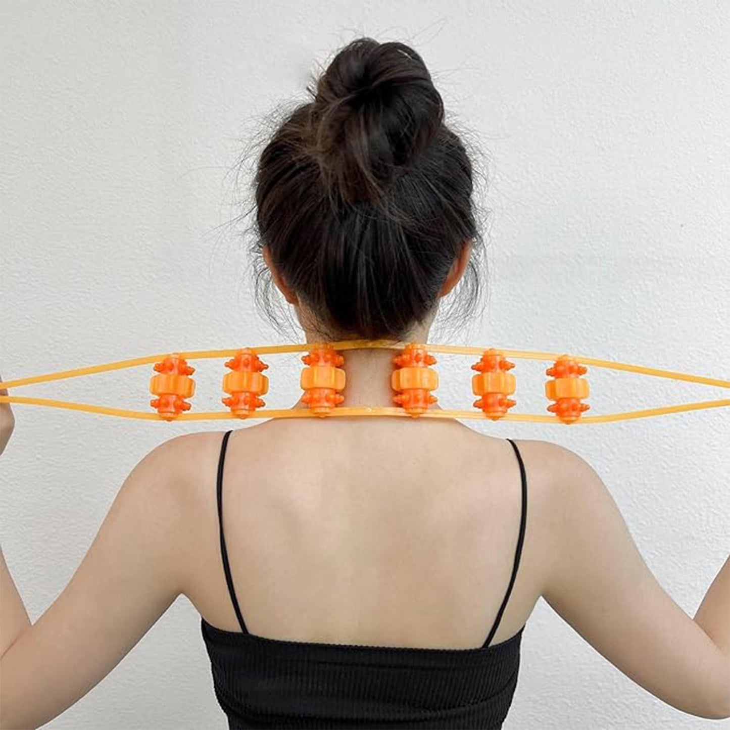 deep tissue back roller for home use held across upper back by woman with bun in black tank top